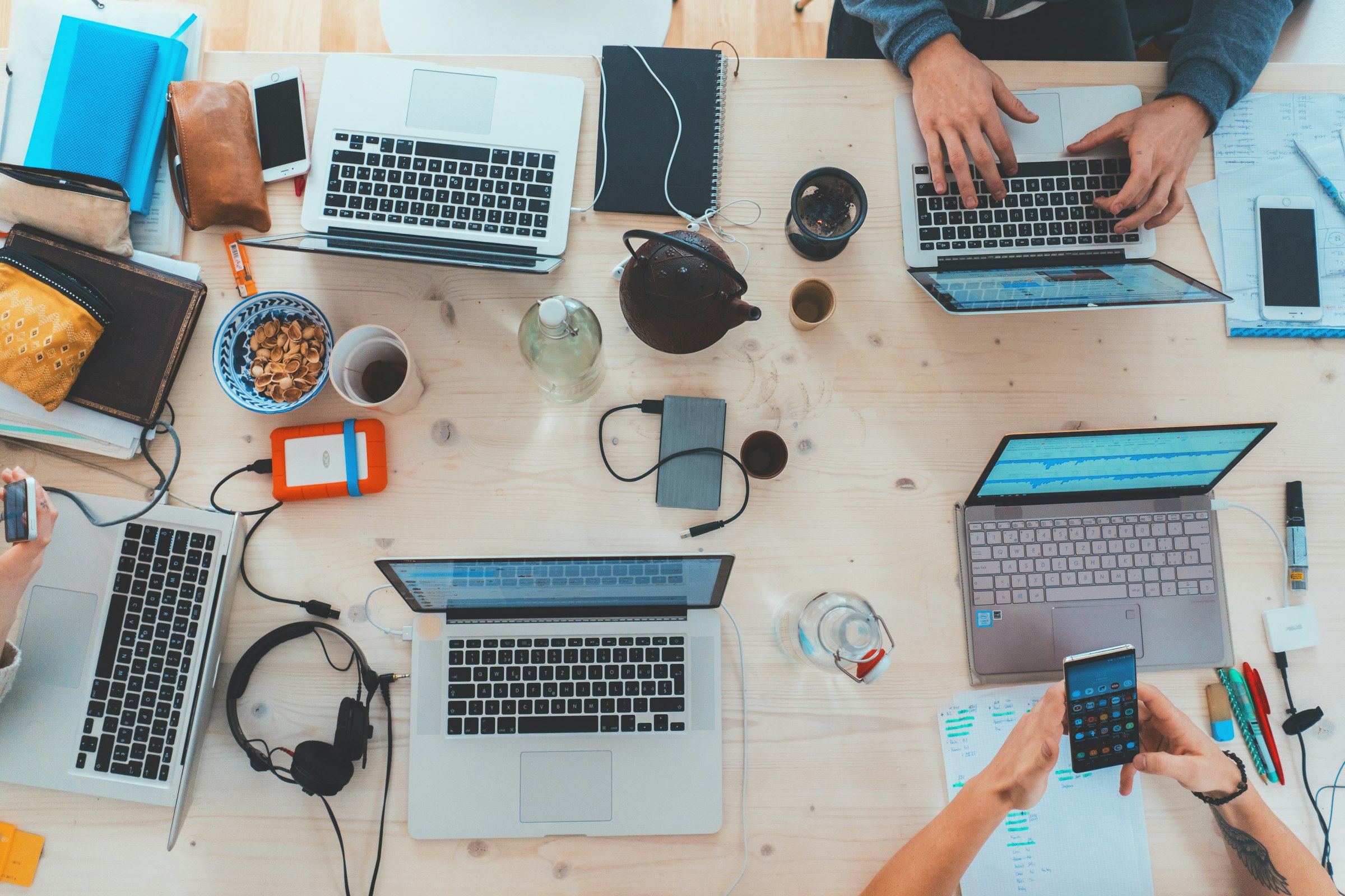 Schreibtisch von oben mit Laptops, Notizbüchern und Kaffee